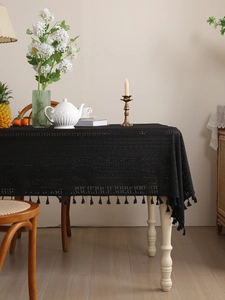 Detail of black hollow lace tablecloth featuring delicate geometric mesh and fringe tassels