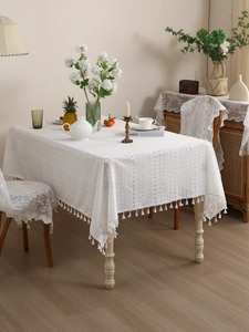 Detail of white crochet lace tablecloth featuring hollow patterns and elegant fringe edges