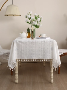 Detail of white hollow lace tablecloth with delicate fringe edge in bohemian style