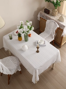 Detail view of white lace tablecloth featuring hollow patterns and tassel fringe trim