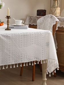 Close-up of white lace tablecloth featuring hollow embroidery and elegant fringe tassels