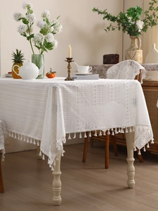Detail of white lace tablecloth with geometric patterns and fringe tassels for dining tables