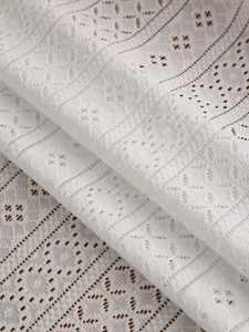 Detail shot of vintage white lace tablecloth with floral hollow patterns and crochet edges