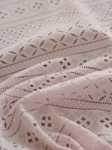 Macro shot of light pink geometric lace tablecloth with intricate hollow-out weaving detail