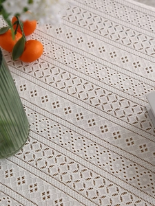 Close-up of geometric hollow lace tablecloth with intricate crochet texture and green decor