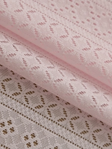 Detailed close-up of pink heart-shaped lace fabric with soft knit patterns and texture