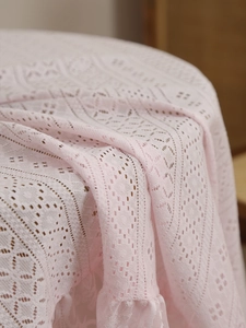 Detail of light pink lace tablecloth featuring hollow geometric patterns and wavy edges