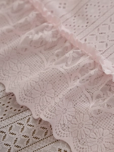 Close-up of pink lace tablecloth featuring floral crochet texture and ruffled edge details