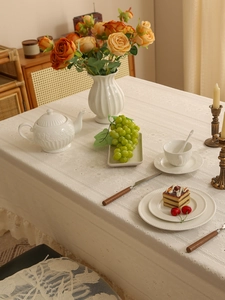 Close-up of elegant white lace tablecloth with floral texture and wavy scalloped edges