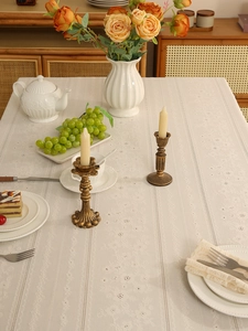 Detailed view of beige lace tablecloth with floral jacquard patterns in a warm home setting