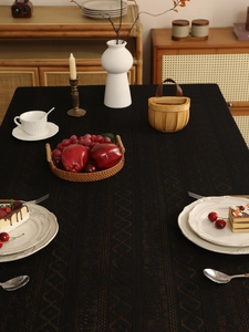 Detail of black rectangular tablecloth with geometric diamond jacquard texture and lace trim