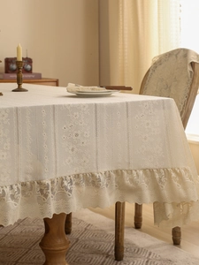 Detailed close-up of retro cream lace tablecloth with floral embroidery and ruffled edges
