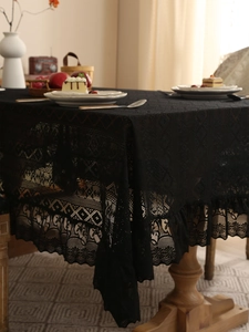 Close-up of black lace tablecloth featuring intricate hollow geometric and floral patterns
