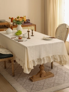 Close-up of vintage beige lace tablecloth with floral embroidery and ruffled edge