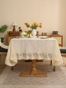 Detail of beige lace tablecloth featuring floral embroidery and wide ruffled lace edges