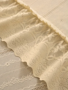 Close-up of beige vintage lace tablecloth with delicate floral crochet and ruffled edges