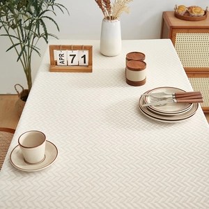 Beige herringbone linen tablecloth draped over a wooden dining table for home decor