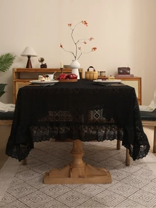 Detailed view of black vintage lace tablecloth with intricate crochet patterns on wood