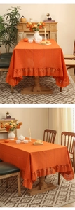 Detail of vintage orange lace tablecloth showing floral jacquard pattern and lace border