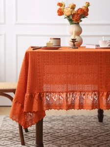 Close-up of orange vintage lace tablecloth with intricate hollow floral patterns and ruffles