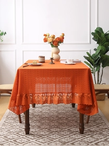 Detailed view of orange cutout embroidery tablecloth with elegant ruffled lace edge detail