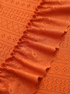 Detailed macro view of orange lace fabric with ruffles and floral geometric patterns
