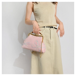 Close-up of pink embroidered handbag with floral patterns, wooden handle and metal clasp
