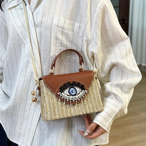 Borsa a tracolla in paglia con patta in pelle e ricamo malocchio con nappe