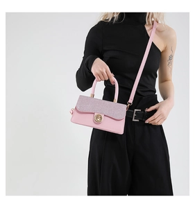 Detailed view of a pink glitter flap crossbody bag with golden twist lock on a model