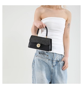 Close-up of black glitter crossbody bag with gold round metal twist lock and top handle
