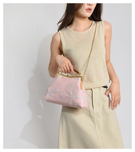 Detail of pink floral embroidery and vintage metal clasp on elegant silk handbag