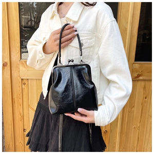 Detail of vintage black pleated leather shell bag with retro metal clasp and round handle