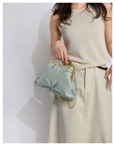 Detail of floral embroidery and gold metal clasp on a mint green vintage evening bag