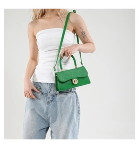 Detail of green woven crossbody bag with gold twist lock and textured flap on model