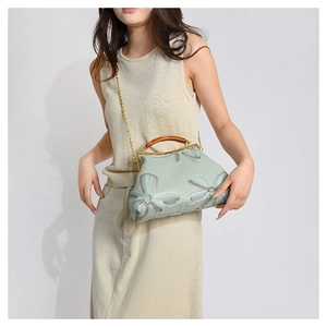 Green vintage frame bag with floral embroidery and amber handle on a model