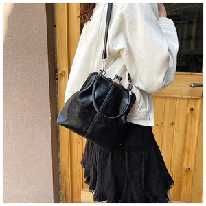 Detail of vintage black shell bag with glossy pleated texture and metal clasp closure