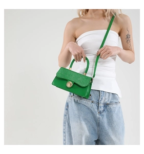 Detail of green crossbody bag with glitter texture and gold rotating metal buckle lock
