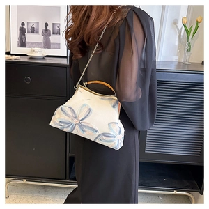 Detailed view of floral embroidery handbag with resin handle and gold chain strap