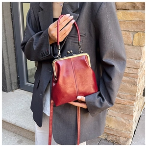 Detailed view of red retro kiss-lock handbag with white stitching and metal clasp handle
