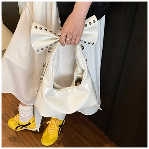 Detail of white patent leather shoulder bag with large bow and silver rivet accents