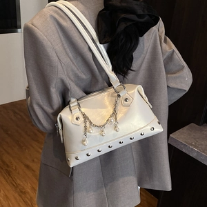 Fashionable beige rivet tote bag with pearls and chain details shown on a model