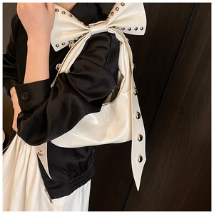Detail of white patent leather shoulder bag with large bow and silver rivet studs