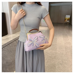 Detail of lavender floral embroidery bag with metal frame and chain strap shown on model