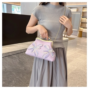 Detail of lavender evening bag with floral embroidery, metal clasp, and chain strap