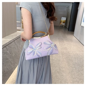Detailed embroidery of purple floral motifs on a vintage clutch bag with a wooden handle
