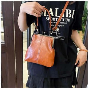 Detailed view of brown kiss-lock handbag with shiny leather texture and metal frame