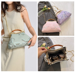 Detail view of floral embroidery handbag with chain strap and interior storage space