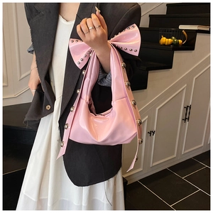 Pink glossy patent leather hobo bag with large bow and silver rivet stud details