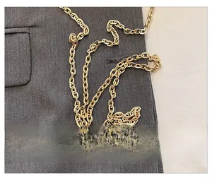 Close-up detail of the elegant golden metal chain strap for a floral evening bag