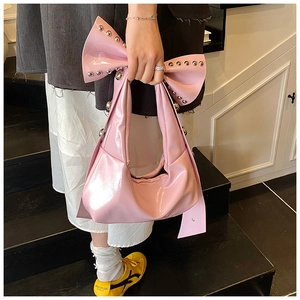 Detail of pink bow handbag with silver studs and glossy leather finish on the shoulder strap